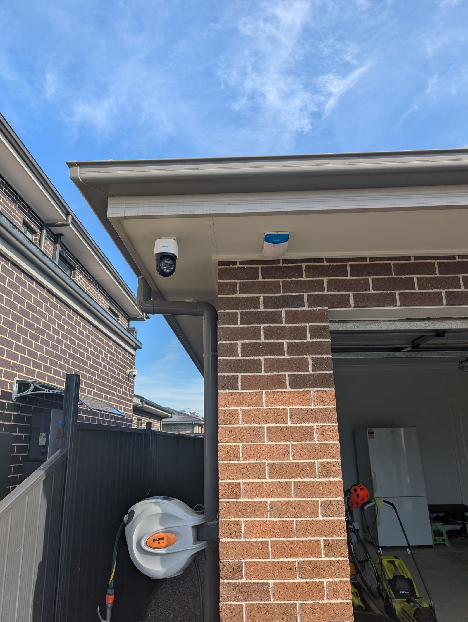 PTZ security camera mounted under the eaves of a new-build home